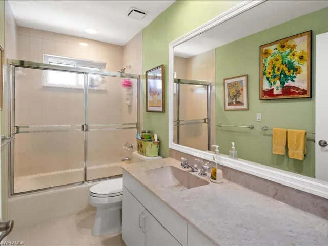 Full bathroom featuring vanity, tile patterned floors, combined bath / shower with glass door, and toilet
