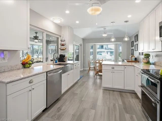Kitchen with white cabinetry, a wealth of natural light, vaulted ceiling, and stainless steel appliances