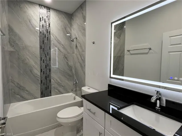 Modern bathroom featuring a lit vanity mirror and a single-basin sink with a chrome faucet