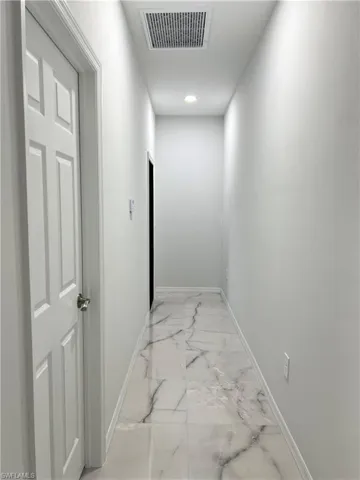 Hallway featuring white panel doors, recessed lighting, baseboard trim, and large format tile flooring