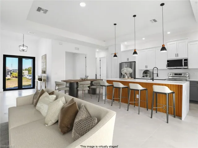Living area featuring a tray ceiling, visible vents, and recessed lighting