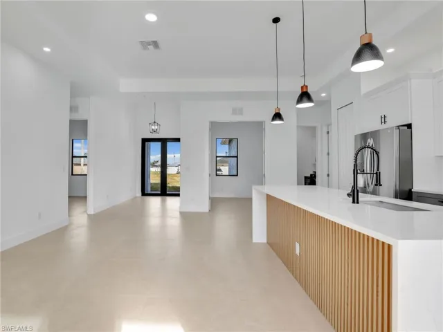 Kitchen featuring recessed lighting, visible vents, light countertops, freestanding refrigerator, and an island with sink