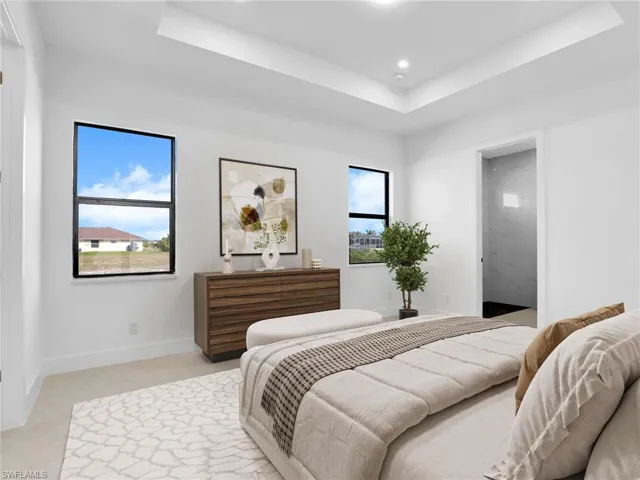 Bedroom featuring a raised ceiling, multiple windows, recessed lighting, and baseboards