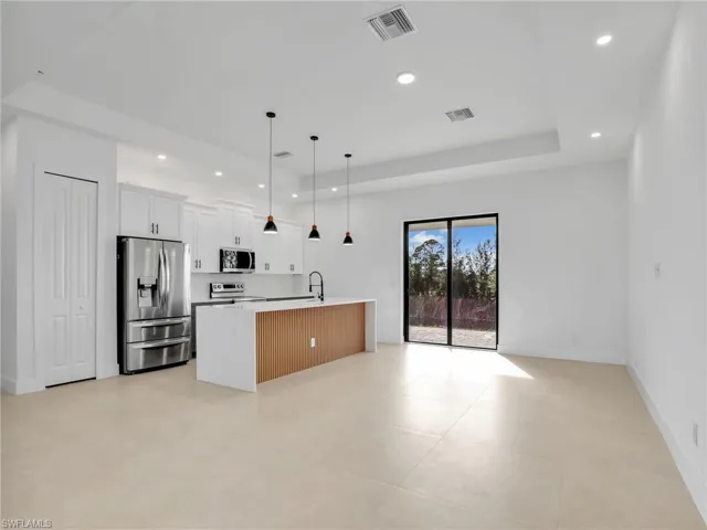 Kitchen featuring recessed lighting, stainless steel appliances, visible vents, open floor plan, and a tray ceiling
