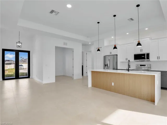 Kitchen featuring stainless steel appliances, recessed lighting, light countertops, visible vents, and a kitchen island with sink