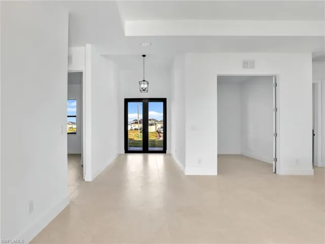 Unfurnished room featuring french doors, visible vents, and baseboards