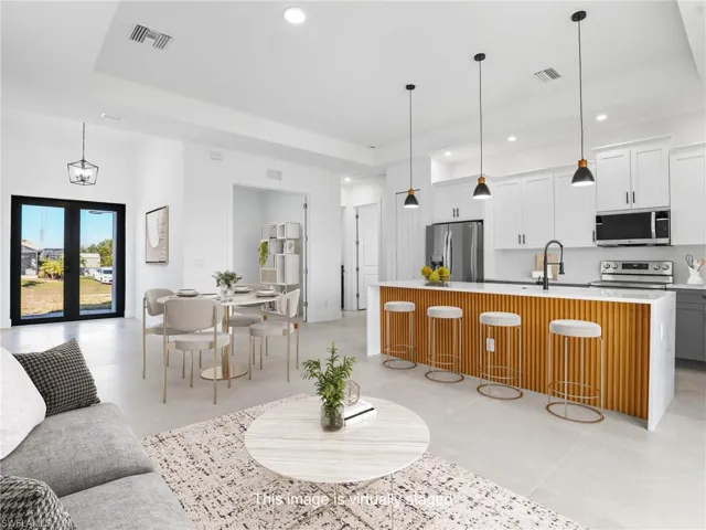 Kitchen with visible vents, appliances with stainless steel finishes, a kitchen island with sink, and light countertops