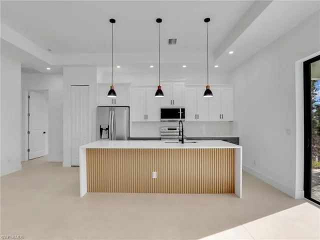 Kitchen with a center island with sink, visible vents, stainless steel appliances, a sink, and recessed lighting