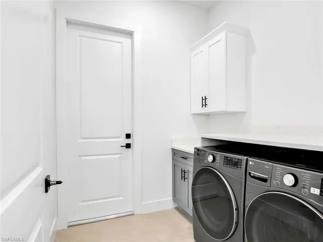 Laundry room with cabinet space, baseboards, and separate washer and dryer