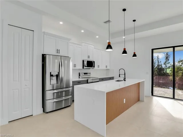 Kitchen featuring recessed lighting, light countertops, appliances with stainless steel finishes, white cabinets, and a sink