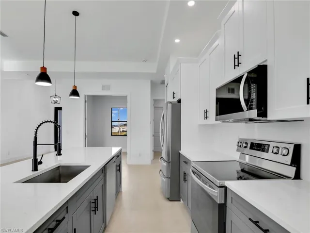 Kitchen featuring recessed lighting, hanging light fixtures, gray cabinetry, appliances with stainless steel finishes, and a sink