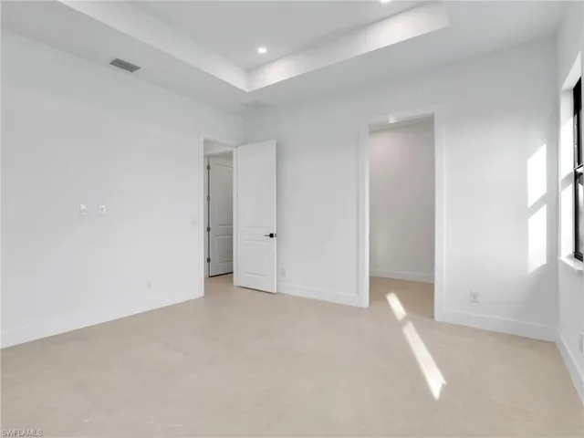 Spare room featuring baseboards, visible vents, a tray ceiling, and recessed lighting