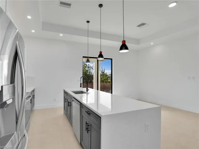 Kitchen featuring freestanding refrigerator, visible vents, a sink, and dishwashing machine