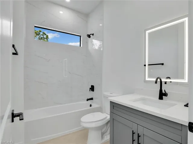 Bathroom with shower / washtub combination, vanity, and toilet