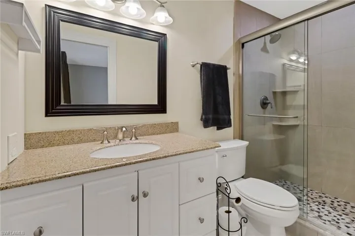 Bathroom featuring vanity, a shower with shower door, and toilet