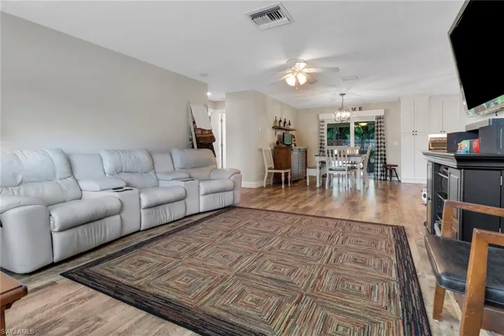 Living room with hardwood / wood-style floors and ceiling fan with notable chandelier