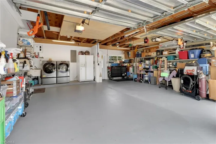 Rare 2 car Garage featuring refrigerator with ice dispenser, a garage door opener, and washing machine and clothes dryer