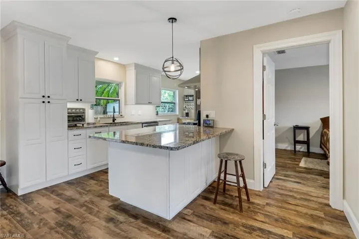 Kitchen with kitchen peninsula, dark hardwood / wood-style flooring, white cabinets, and sink