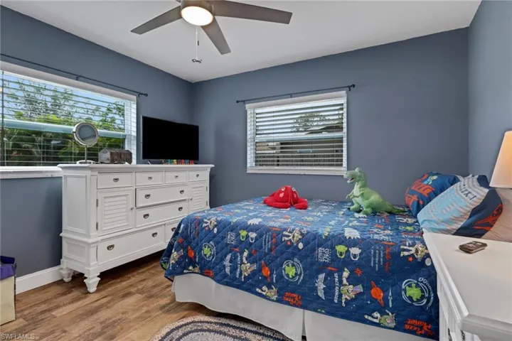 Bedroom with multiple windows, ceiling fan, and light hardwood / wood-style floors