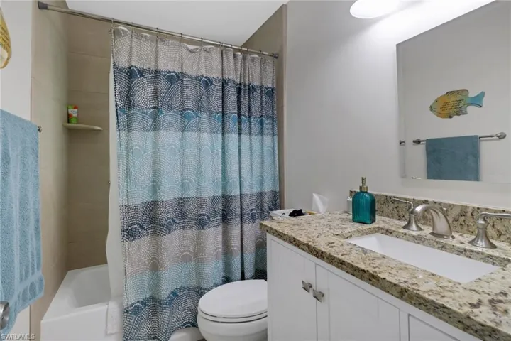 Full bathroom with vanity, shower / bath combo, and toilet