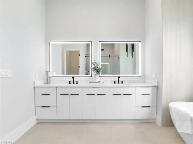Full bath with double vanity, a freestanding bath, an enclosed shower, and a sink