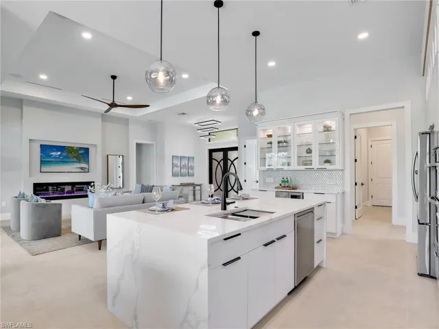 Kitchen featuring stainless steel appliances, tasteful backsplash, a raised ceiling, white cabinets, and a sink