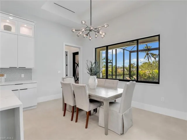 Dining area featuring a chandelier, a raised ceiling, and baseboards