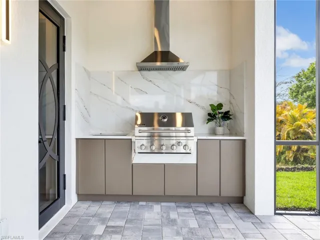 Kitchen featuring wall chimney exhaust hood, tasteful backsplash, and gray cabinetry