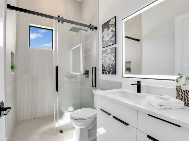 Bathroom featuring a shower stall, toilet, and vanity