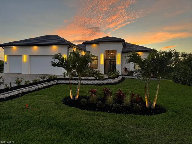 View of front of property with a garage, decorative driveway, a front lawn, and stucco siding