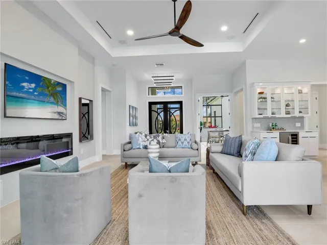 Living area with wine cooler, a raised ceiling, a bar, and recessed lighting