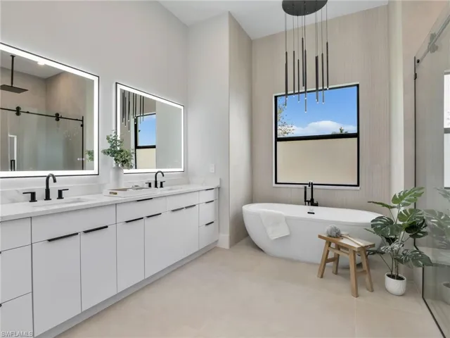 Full bathroom featuring double vanity, a soaking tub, a stall shower, a healthy amount of sunlight, and a sink