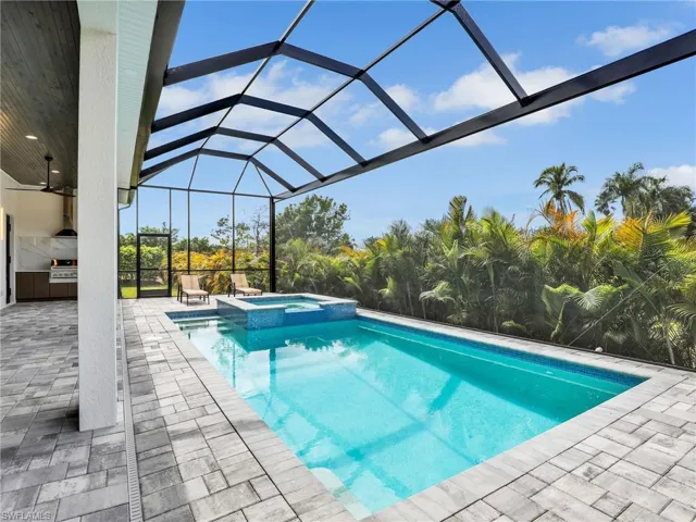 View of swimming pool featuring a patio area, an outdoor kitchen, a lanai, and a pool with connected hot tub