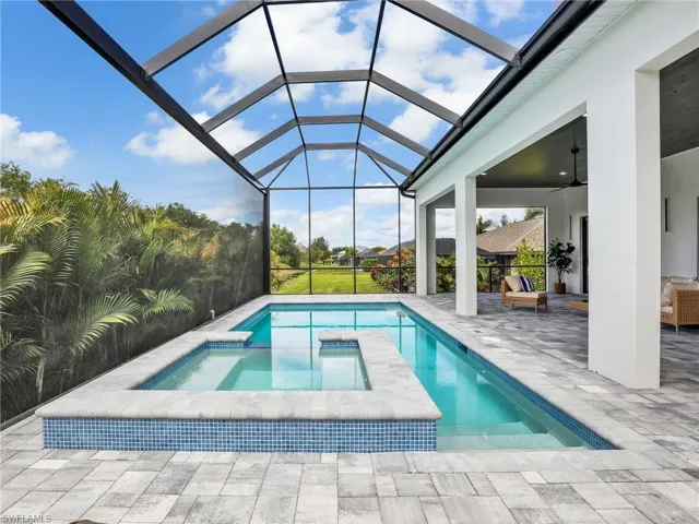 View of pool featuring ceiling fan, a patio, a lanai, and a pool with connected hot tub