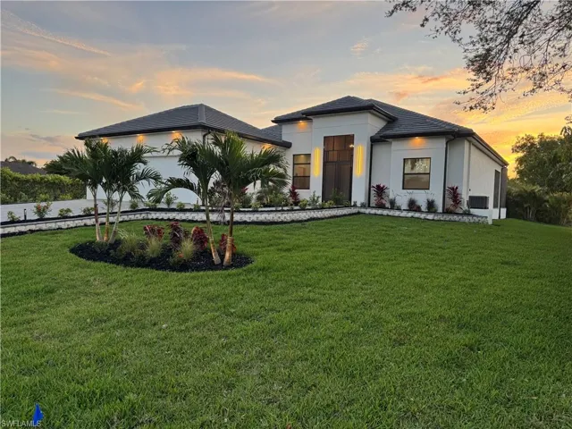 View of front facade featuring a garage, a front yard, and stucco siding