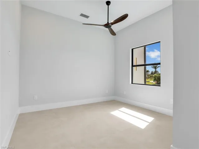 Empty room featuring ceiling fan, visible vents, and baseboards