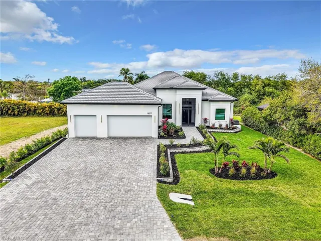 View of front of property featuring an attached garage, a front lawn, decorative driveway, and stucco siding