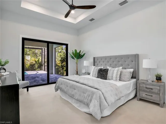 Bedroom featuring a ceiling fan, access to outside, a raised ceiling, and visible vents