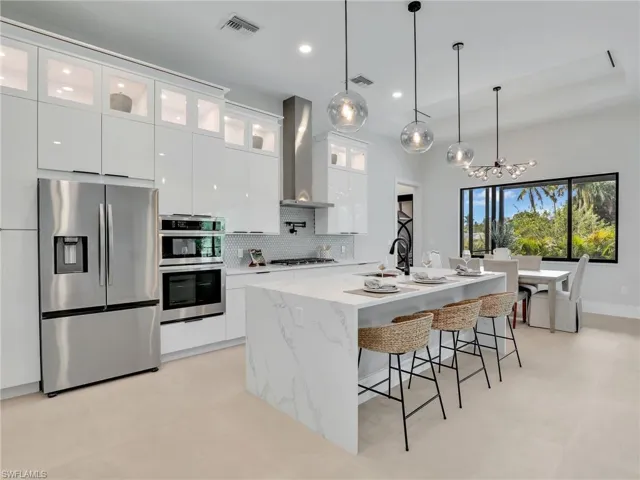 Kitchen featuring appliances with stainless steel finishes, visible vents, wall chimney exhaust hood, and white cabinetry