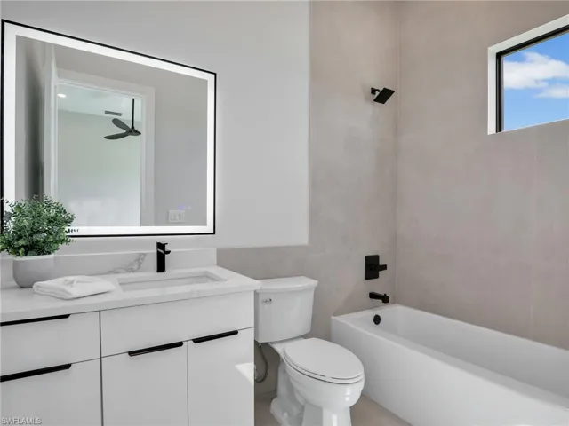 Bathroom featuring tile walls, vanity, toilet, and bathing tub / shower combination