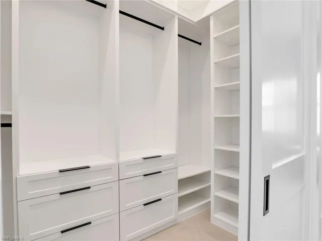 Spacious closet featuring light tile patterned floors and a barn door