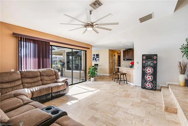 Living area featuring ceiling fan, lofted ceiling, and stone tile floors