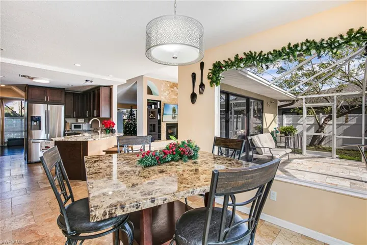 Dining space featuring stone tile floors, a fireplace, and recessed lighting