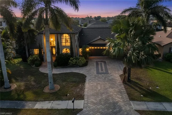 View of front of property with decorative driveway, a yard, and a garage