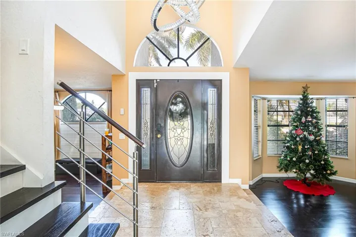Entryway with stone tile flooring, stairway, and a towering ceiling