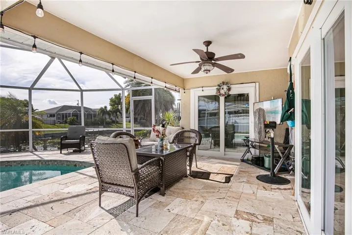 View of patio featuring a ceiling fan, glass enclosure, an outdoor pool, and a sunroom