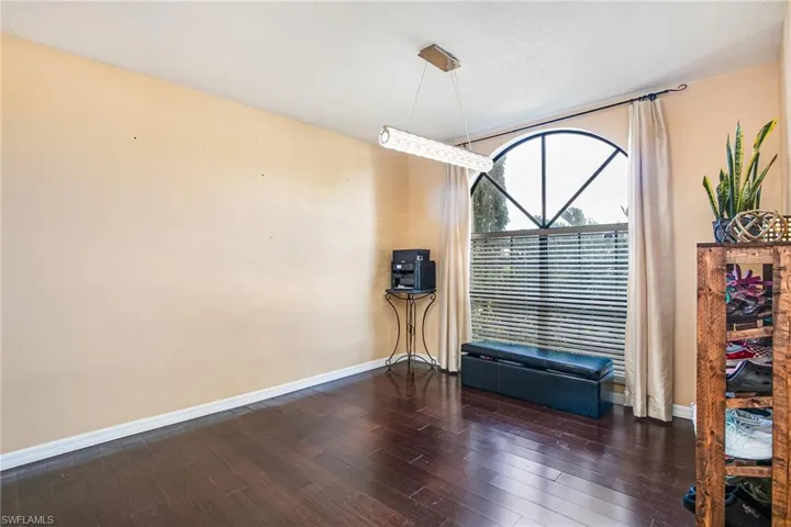 Unfurnished room with baseboards and dark wood-style flooring