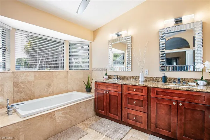 Bathroom with double vanity, a bath, lofted ceiling, and light tile patterned floors