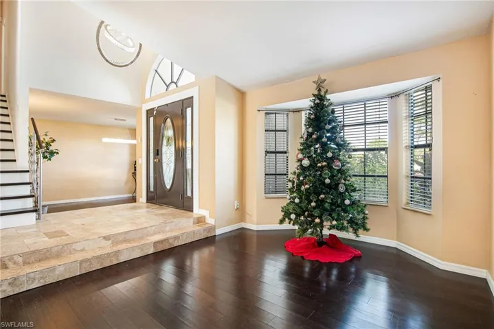 Entrance foyer with stairs, dark wood-type flooring, and vaulted ceiling