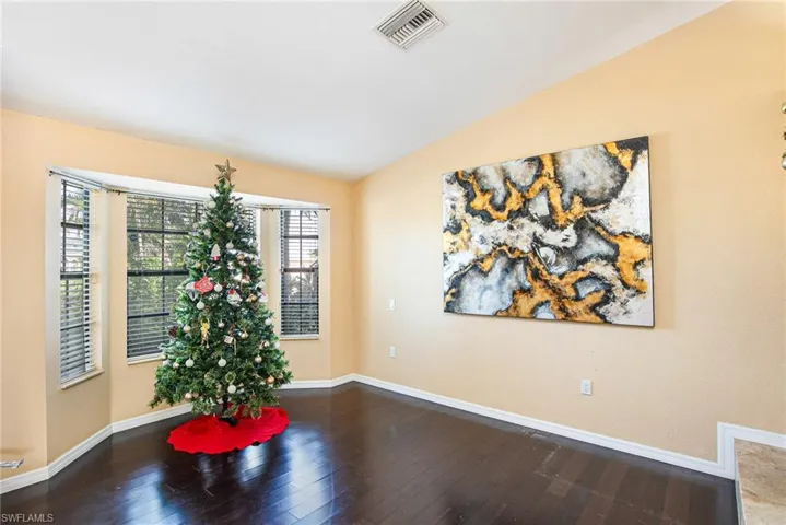 Unfurnished room with dark wood-style floors and vaulted ceiling